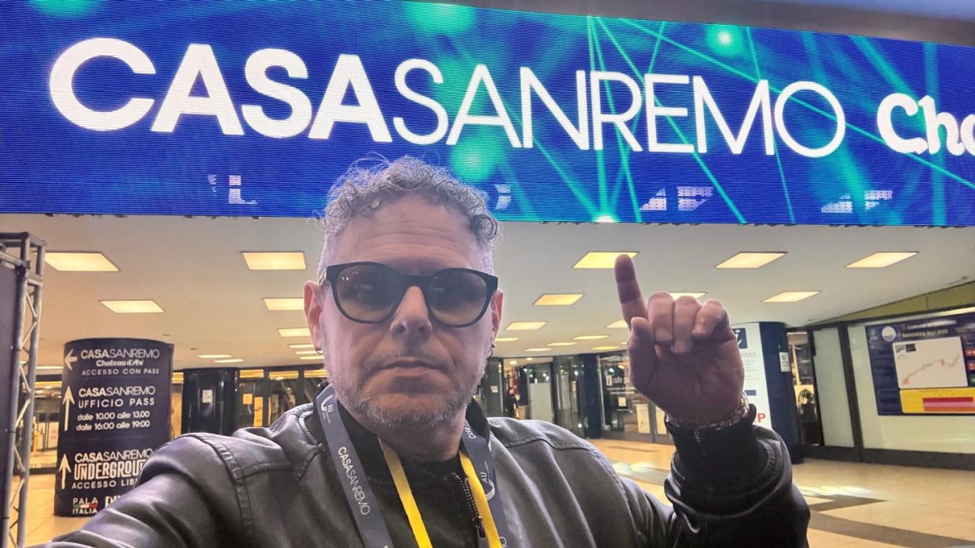 Band performing on stage with a guitarist, vocalist, drummer, and keyboardist.